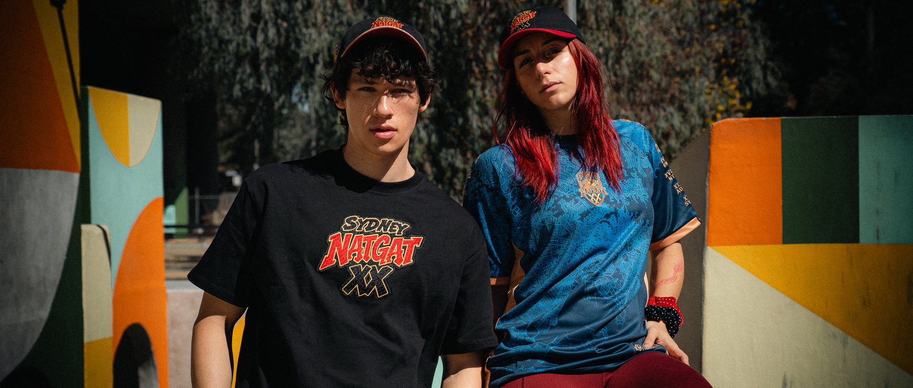 Two athletes at a park wearing the NATGAT XX bundle: the tee, the jersey and the cap